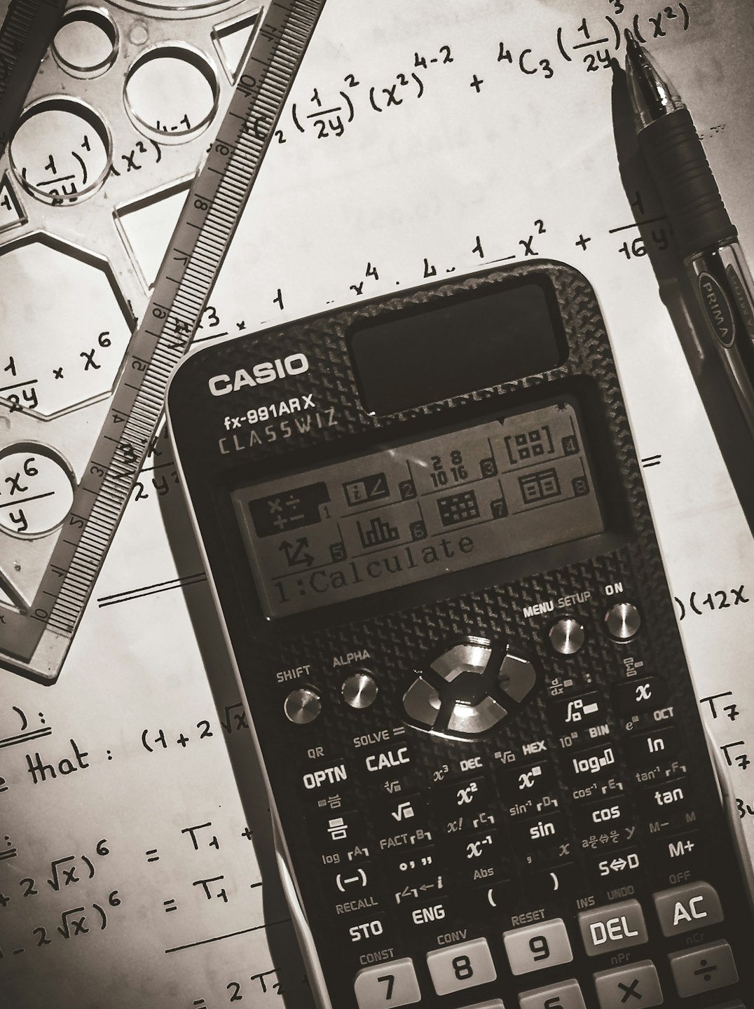 Calculator, ruler, stencil, and pen on paper with math equations.